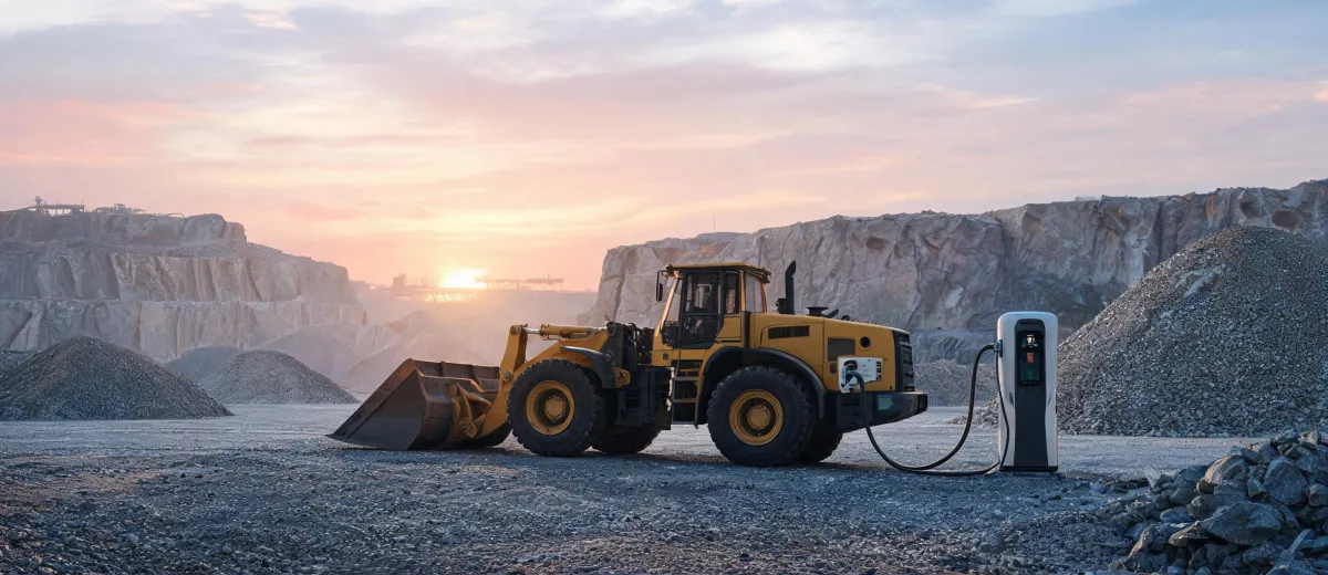 Battery-electric wheel loader charging beside quarry haul road