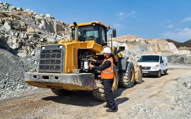 Field technician servicing wheel loader on quarry haul road